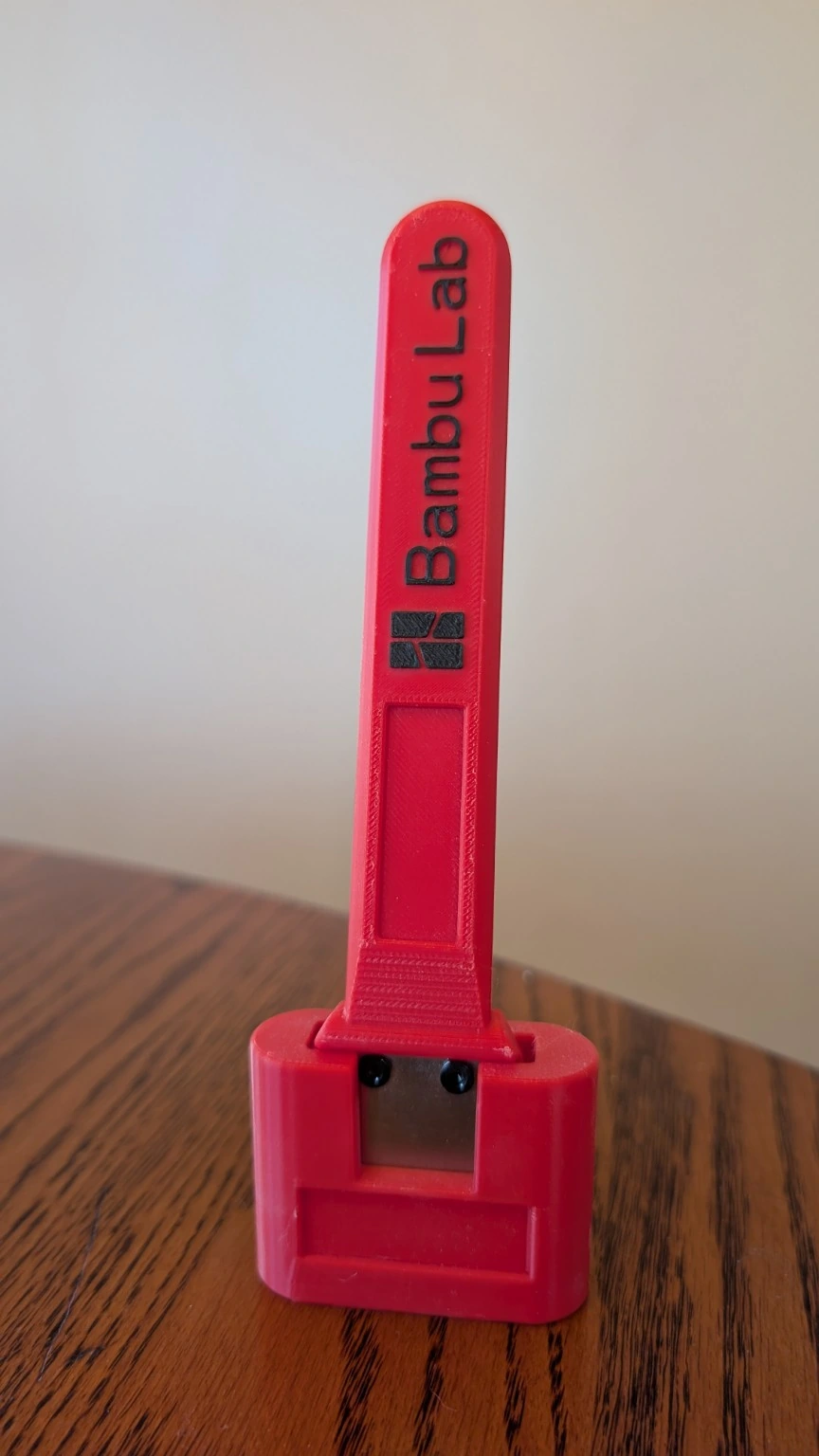 Aaron’s red and black Bambu Lab scraper handle in its red holder, with a fitted metal blade
